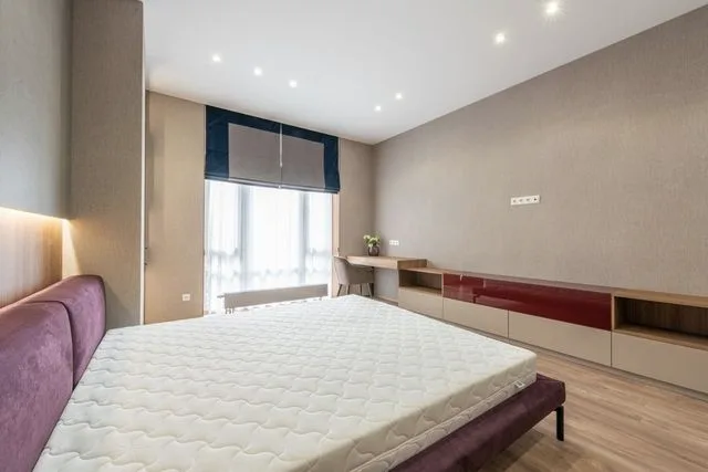 A bare mattress on a bed frame in an otherwise stripped bedroom